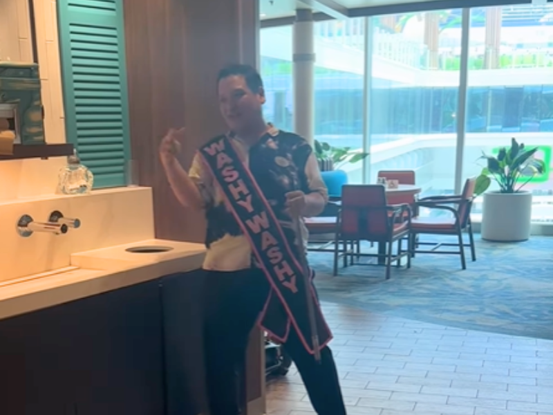A man dances near a wash basin inside a cruise ship