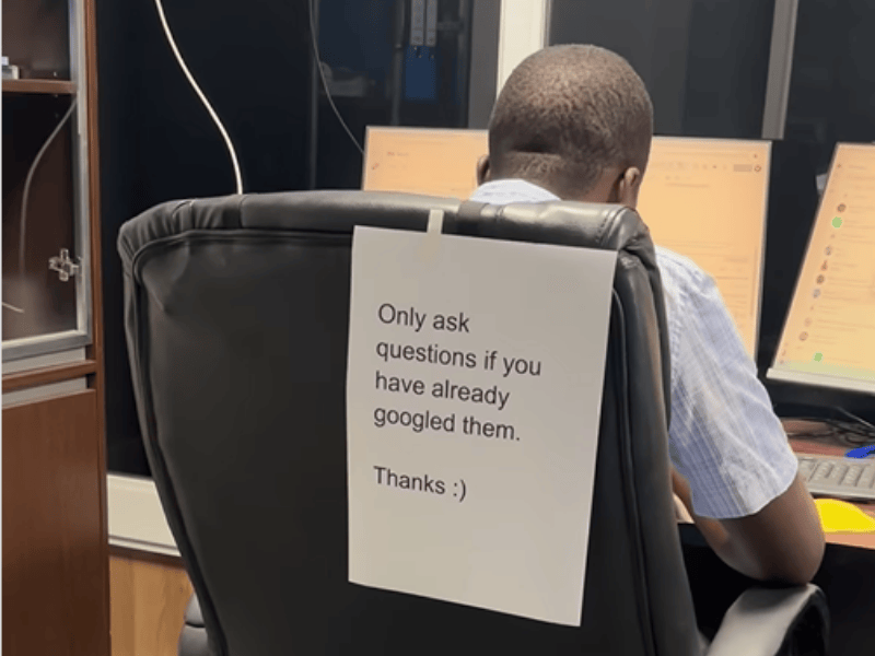 A man works at his desk and has a note on his chair to avoid disturbance