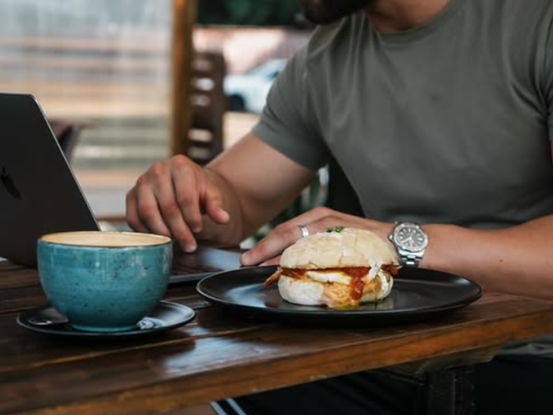 A man works on his laptop while enjoying breakfast