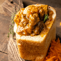 A meat bunny chow on a wooden surface with a carrot salad