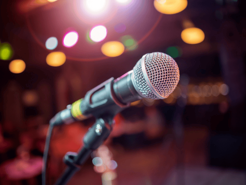 A microphone on stage against a background signifying a performance