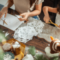 A mother and daughter cutting snowflakes out of paper