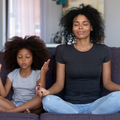 A mother and daughter do yoga poses together on the couch