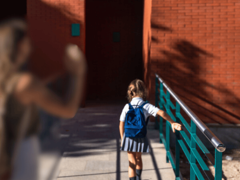 A mother saying goodbye to her child walking into school