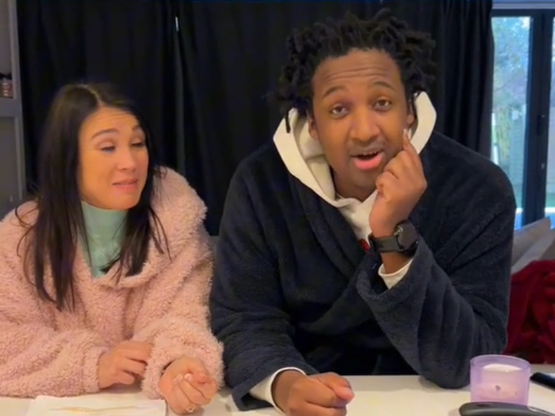 A multi-racial couple standing in the kitchen wearing robes