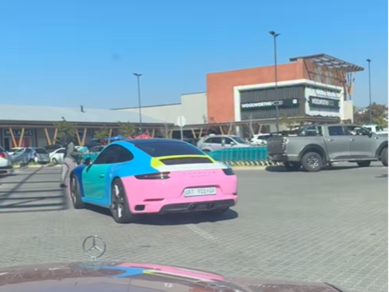 A colourful Porsche 911 Carrera T driving around a car park