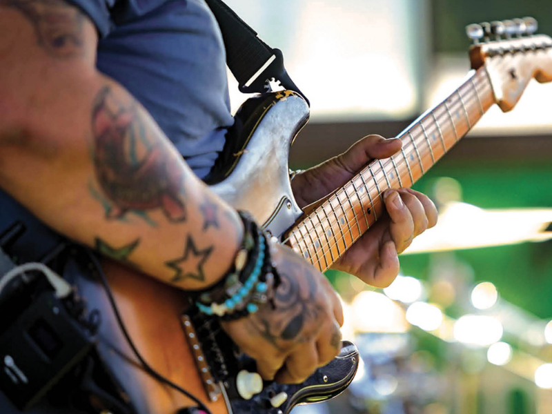 A musician with tattoos on his arm plays the guitar