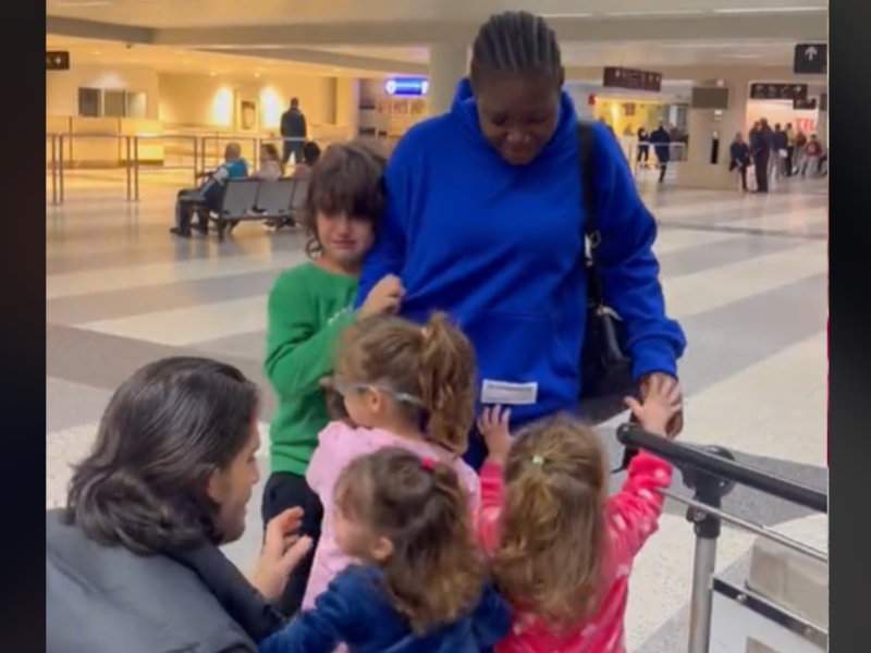 A nanny stands with the kids she cares for at airport