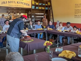 A person carves a turkey while diners wait to eat at JBJ Soul Kitchen