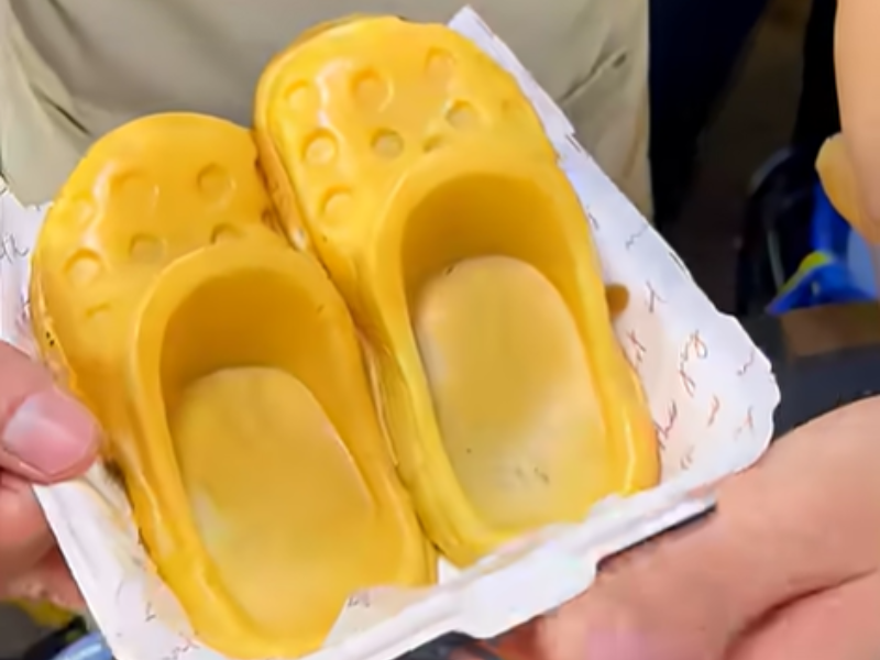 A person hands a plate of waffles shaped like crocs