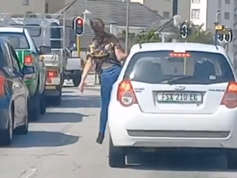 A person hanging off the side of a car on the road