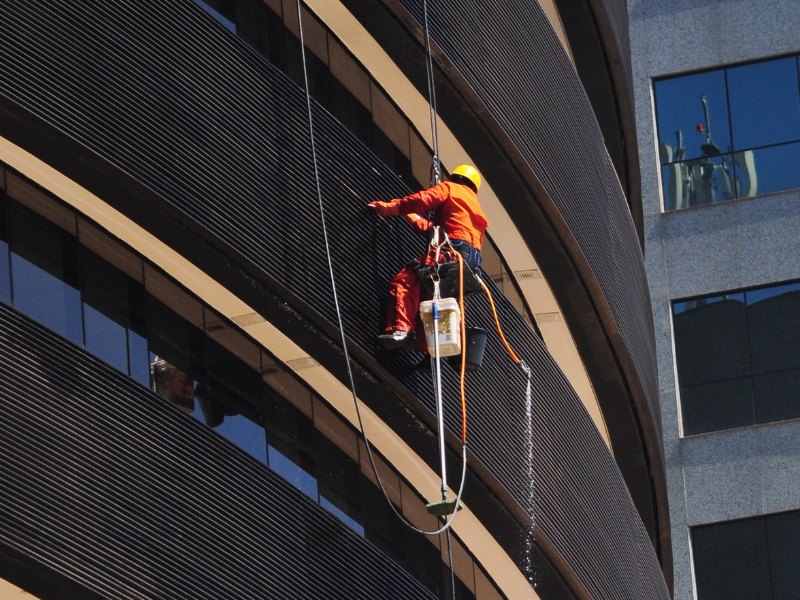 A person hanging on the building washing windows