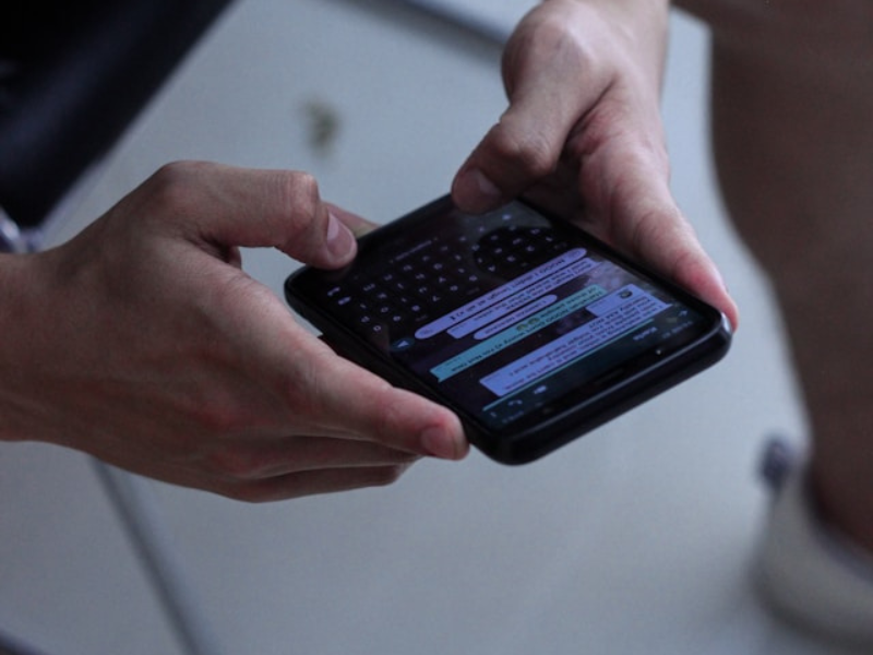 A person holding a black iPhone typing a message