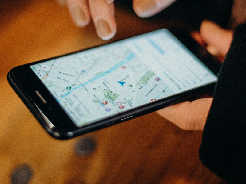 A person holding a black smartphone with Google maps open