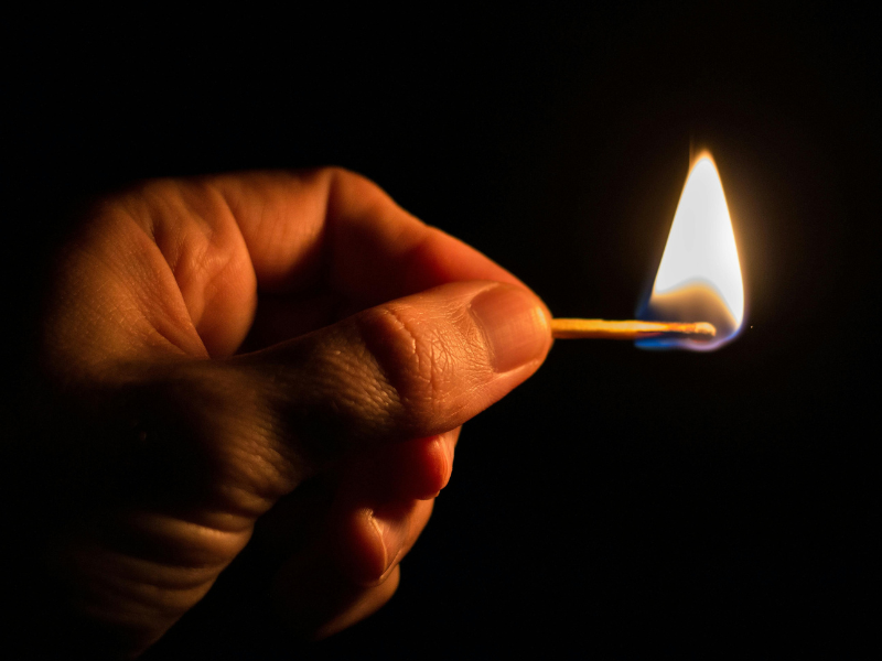 A person holding a lit matchstick