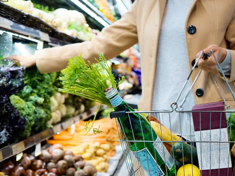 A person holding a shopping basket with things inside