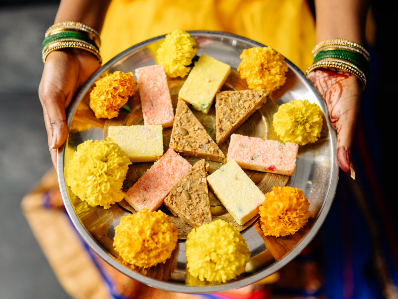 A person holding stainless steel plate with traditional desserts