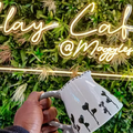 A person holds a handcrafted milk jug against a light sign