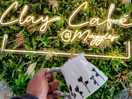 A person holds a handcrafted milk jug against a light sign