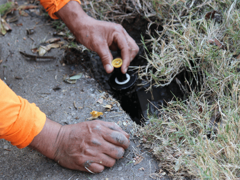 A person installing a new sprinkler head in the ground