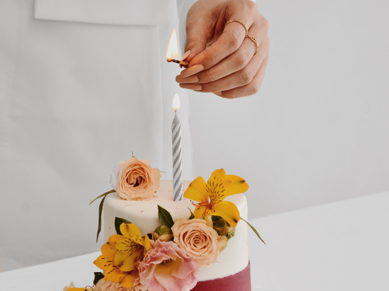 A person lighting a candle on the cake