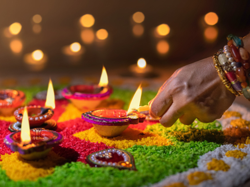 A person lights a traditional diya lamp for Diwali celebration