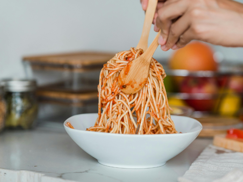 A person mixing a bowl of spaghetti