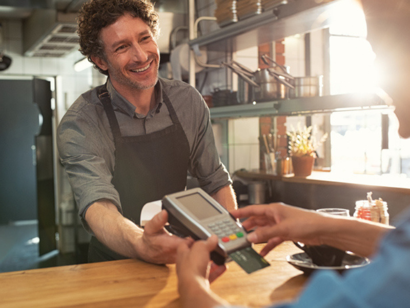 A person paying a waiter with a card machine
