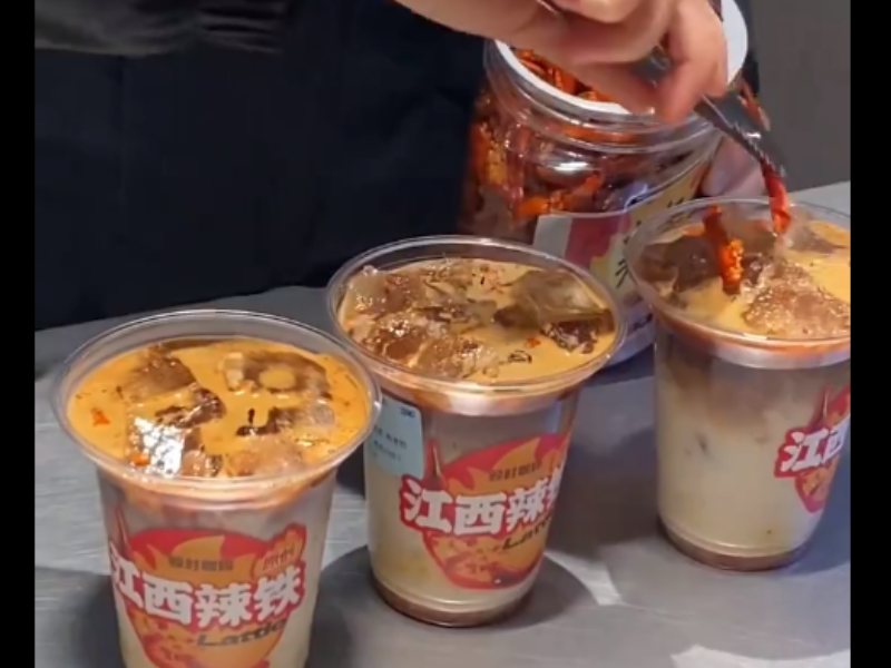 A person placing slice chilli into a cup of iced latte