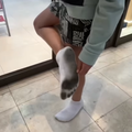 A person shows off the under part of their white socks inside a shopping centre