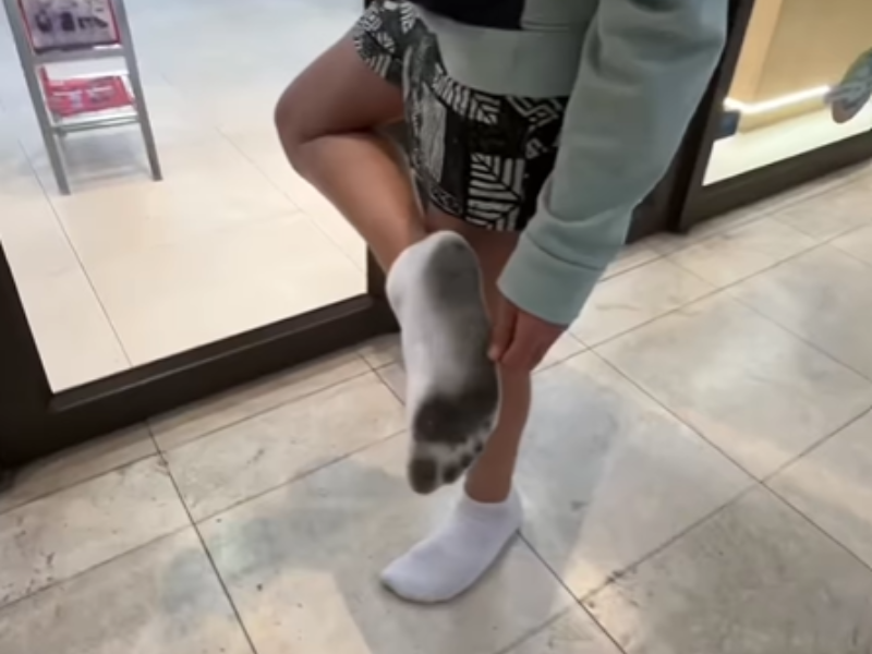 A person shows off the under part of their white socks inside a shopping centre