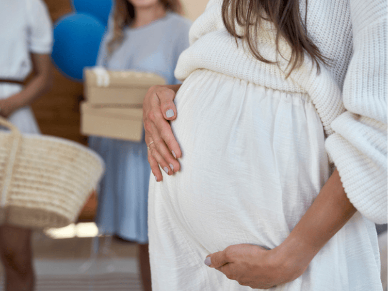 A pregnant mother sits at her baby shower with friends