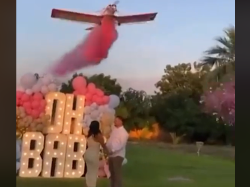 A plane flies overhead a couple at gender reveal party
