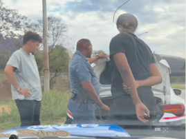 A policeman stops a car and talks to two men