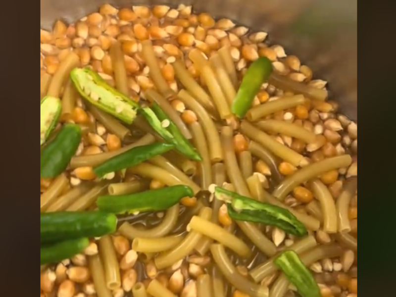 A pot filled with popcorn seeds macaroni and green chilli