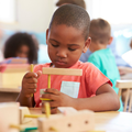 A pupil working at a classroom desk with wooden shapes
