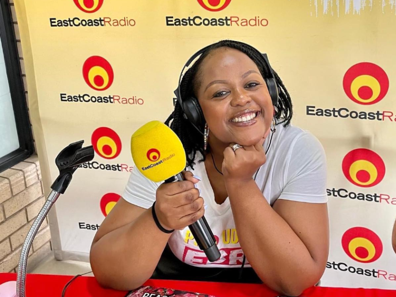 A radio presenter with headphones and mic in hand