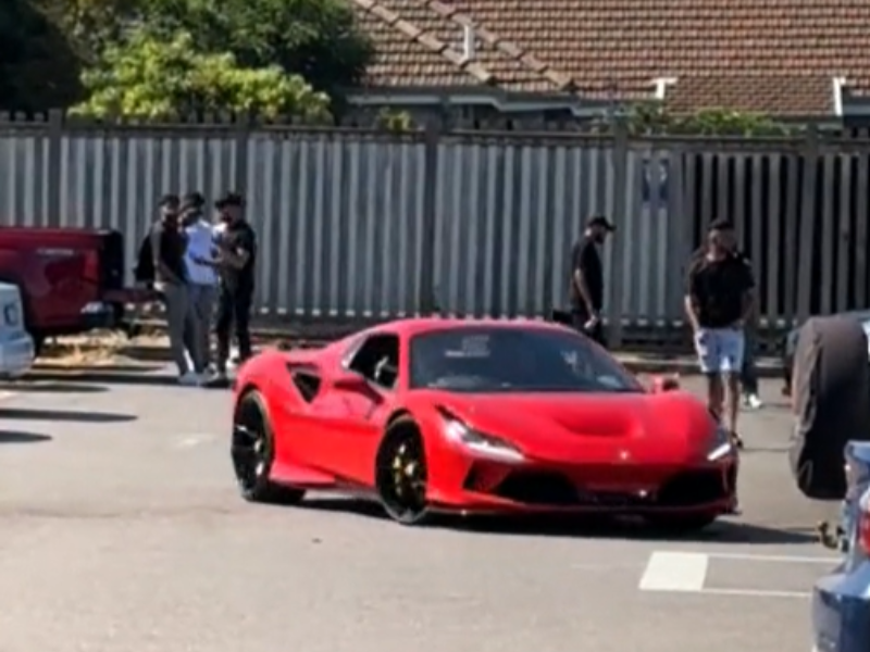 A red Ferrari driving into a college parking lot