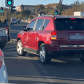 A red Jeep cuts into a lane before a traffic light in Johannesburg