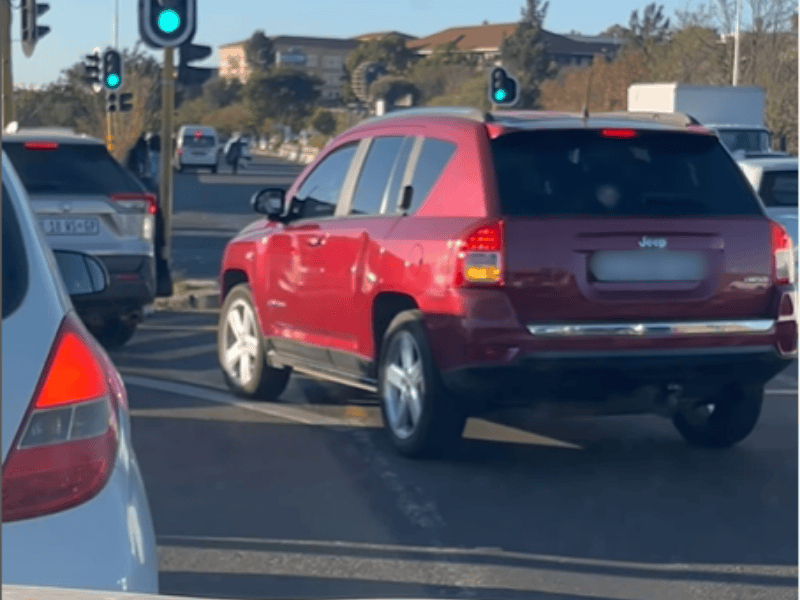 A red Jeep cuts into a lane before a traffic light in Johannesburg