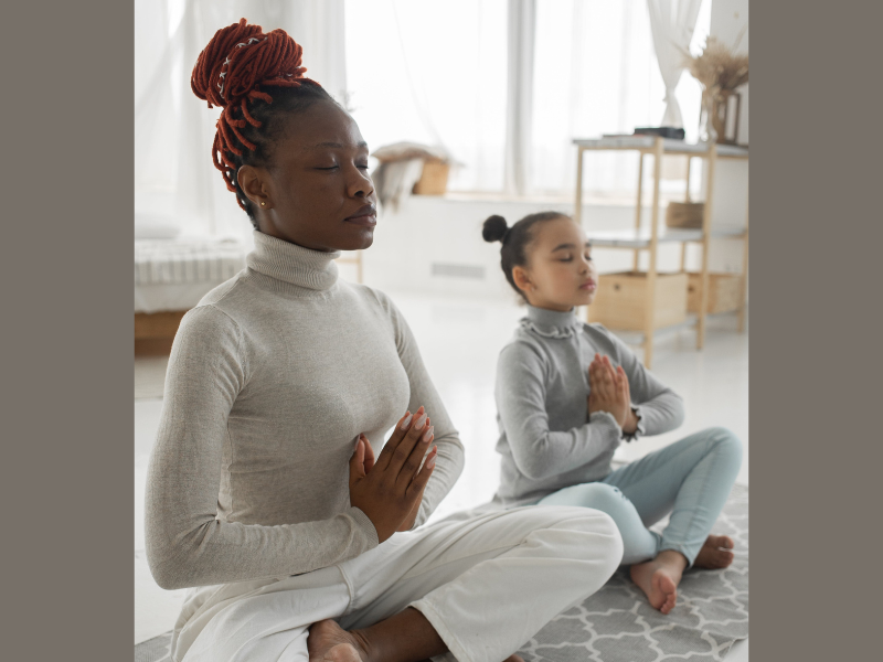 A relaxed black woman with her young daughter practicing yoga