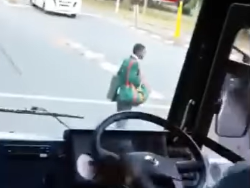 A school boy stands in the middle of the road