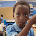 A schoolgirl wearing a blue uniform talks to her teacher