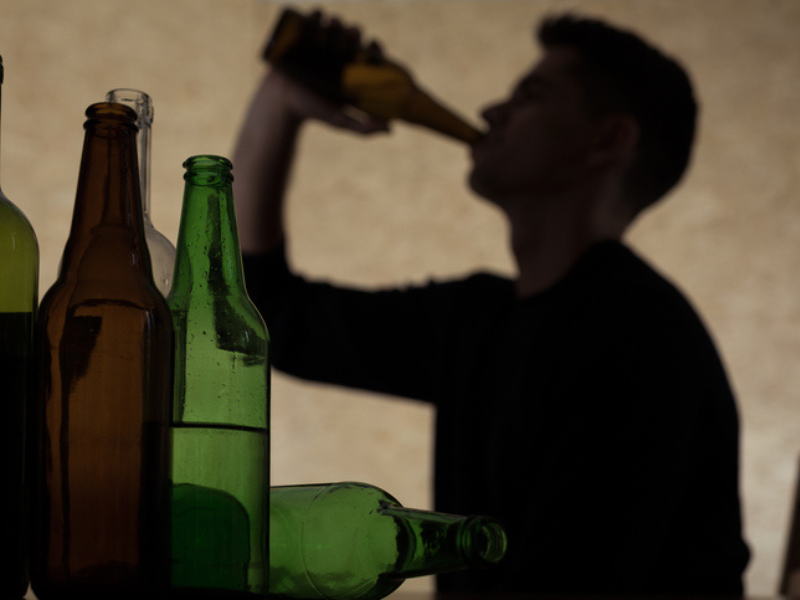 A silhouette of a teenage boy drinking beer