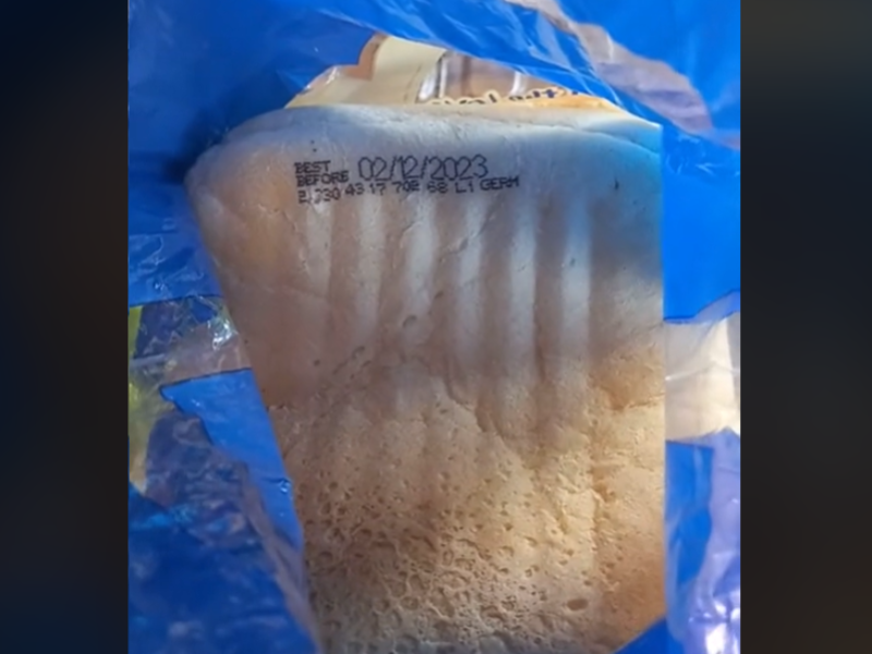 A slice of white bread in a packet with the best before date printed on the slice