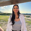 A smiling woman stands close by the beach