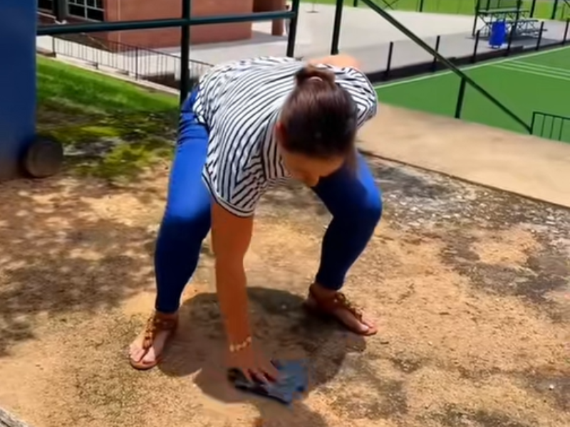 A teacher dusts the ground with a rag cloth