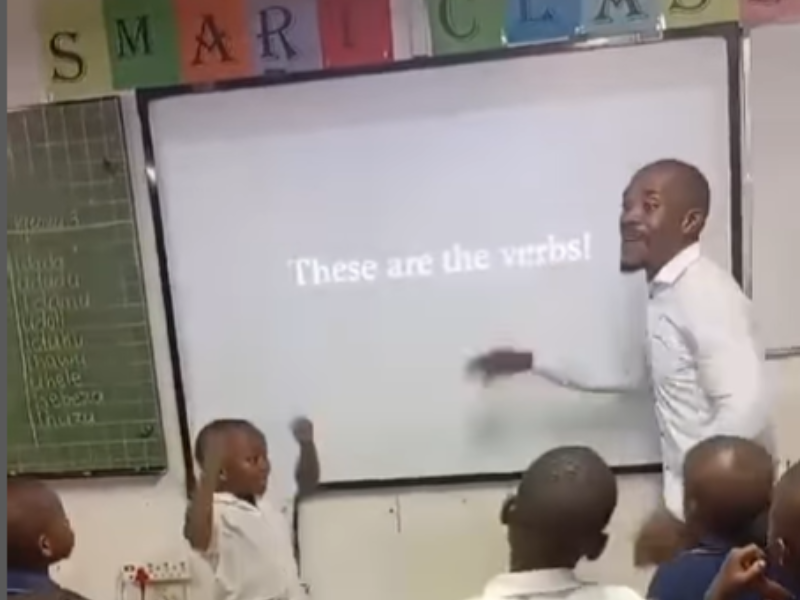 A teacher teaching his class about verbs in an upbeat way