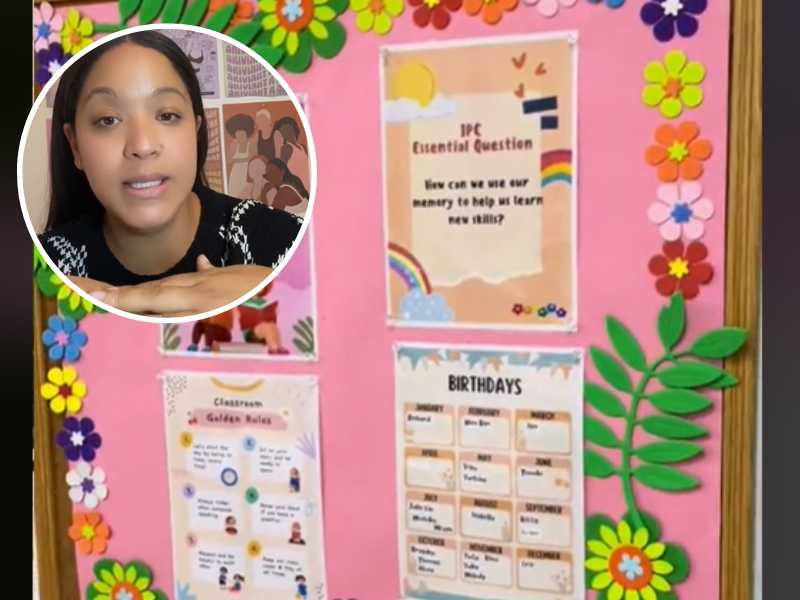 A teacher wearing a black sweater and her classroom noticeboard at the back