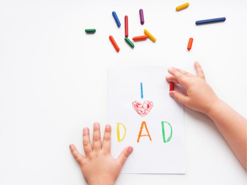 A toddler draws a greeting card for father